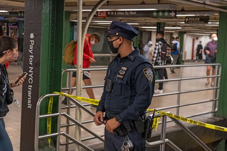 A stock photo of an NYPD officer talking to a subway passenger